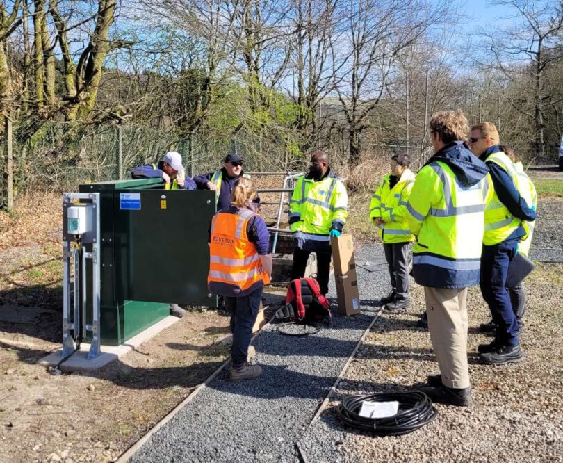 Engineers and technicians gathered around water monitoring and dosing equipment during a site installation.